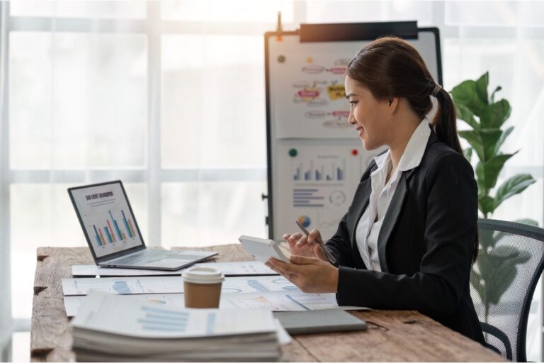 A credit analyst reviewing financial charts and reports at a desk with a laptop and calculator